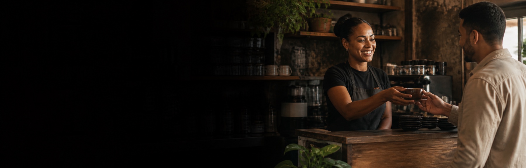 A café barista handing a freshly prepared coffee to a customer.